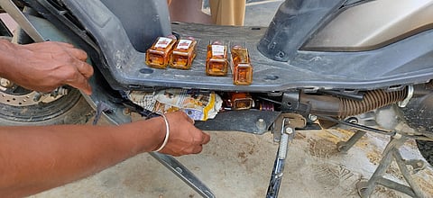 Nip of alcohol hidden in the footrest of a Suzuki moped