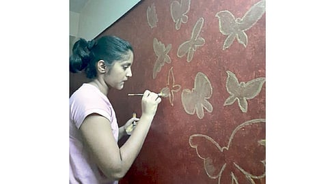 घरातल्या भिंतींवर फुलपाखरांचा थवा चितारताना गौरी जगताप.