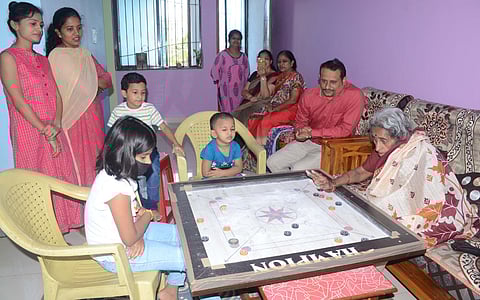 old grandmother plays carom with grandchildren and great grandchildren in belgum