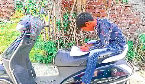 भंडारा : घराबाहेर दुचाकीवर बसून अभ्यास करताना मुलगा.