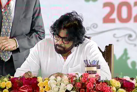 Janasena chief Pawan Kalyan signs the register after taking oath as a Minister in the Andhra Pradesh government