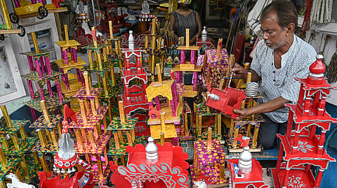 An artist gives final touches to 'Rath' (chariot) of Lord Jagannath, Lord Balbhadra and Goddess Subhdhra as he waits for customers on the eve of Rath Yatra festival, in Kolkata