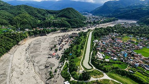 Damaged houses stand precariously near the swollen, debris-choked banks of the Trishuli River after flash floods in Nepal's Nuwakot district, on Wednesday | PTI