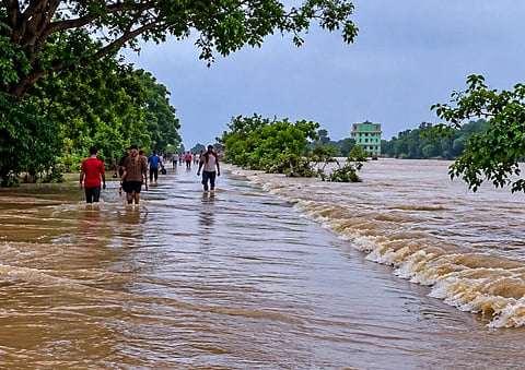 People wade through floodwater on an inundated road following rainfall as water from the Salandi River enters villages, in Bhadrak district, Odisha | File image/PTI