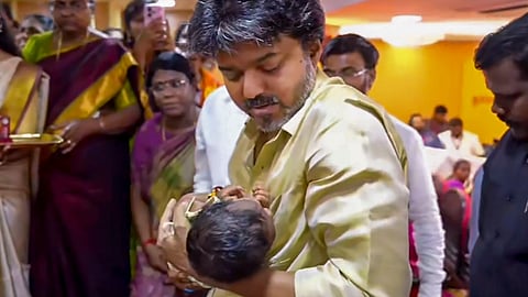 Tamil Nadu CM C Joseph Vijay embraces a baby during the launch of the state government's 'Thai Maman Thanga Mothiram' scheme, in Madurai, on Monday | PTI