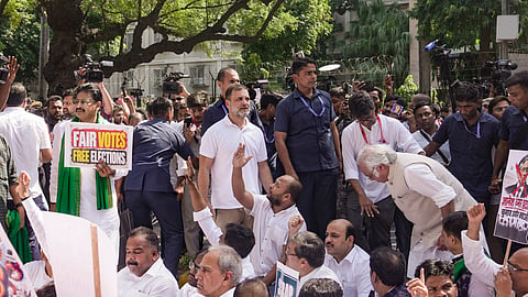 Rahul Gandhi and other INDIA bloc leaders and supporters sit on the road to protest during their march, in New Delhi, on Tuesday | PTI