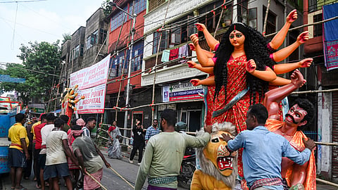 Workers carry an idol of goddess Durga to a 'Puja Pandal' for installation during 'Mahalaya' ahead of Durga Puja festival, at Kumartully, in Kolkata | PTI