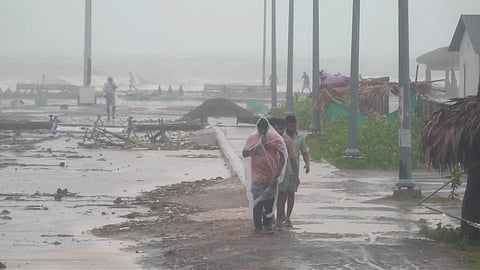 People walk amid strong winds and rainfall at a coastal area during Cyclone Arnab's landfall, in Kakinada, Andhra Pradesh, on Wednesday | PTI