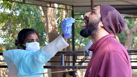 A healthcare worker takes the oral swab sample of a man for COVID testing amid concerns of rising Omicron-driven Coronavirus cases,