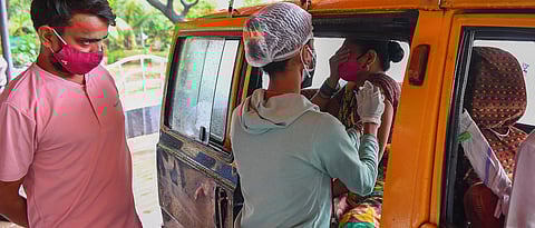 A youth looks at a medical staff as she inoculates his mother sitting inside a taxi with a dose of the Covishield AstraZeneca-Oxford's Covid-19 coronavirus vaccine at a drive-in vaccination facility in Mumbai July 13, 2021. (AFP)