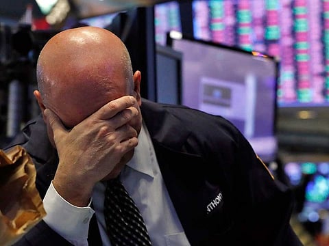 A trader has his head in his hand on the floor of the New York Stock Exchange.