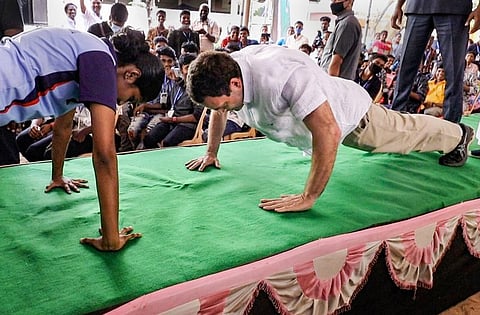 Congress leader Rahul Gandhi does push-ups with a school student obliging her challenge, at St. Joseph's School, during his election campaign for Tamil Nadu Assembly polls, at Mulagumoodu in Kanyakumari district, in a file photo.