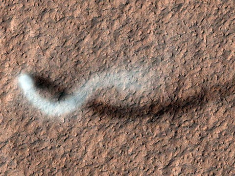 As the camera High-Resolution Imaging Science Experiment (HiRISE) pans over large swaths of Mars' surface, it occasionally discovers surprises like this towering dust devil, which was captured from 185 miles (297 kilometers) above the ground. The length of this whirlwind's shadow indicates that it was more than half a mile (800 meters) high – about the size of the United Arab Emirate's Burj Khalifa, the tallest building on Earth.
