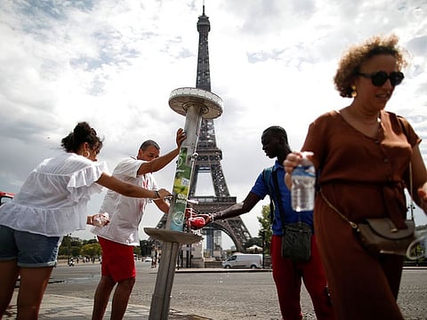 People cool off next to a fountain near the Eiffel Tower as a heatwave rolls over Paris.