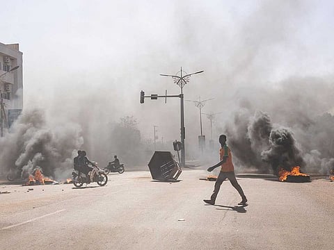 Earlier this year in Ouagadougou, the capital of Burkina Faso, a man navigates through blazing barricades on central avenues. These demonstrators, advocating for the army's role, protested against President Marc Christian Kabore