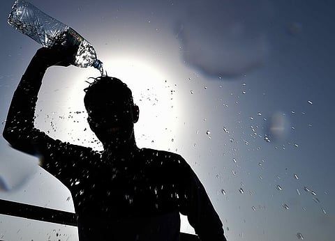 A boy tries to cool himself by pouring the water on his head to beat the heat as temperatures rise