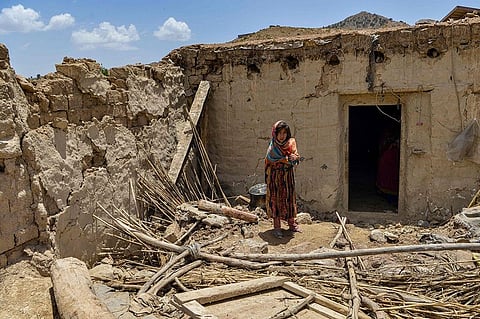 A child stands besides a house damaged by an earthquake in Bernal district, Paktika province