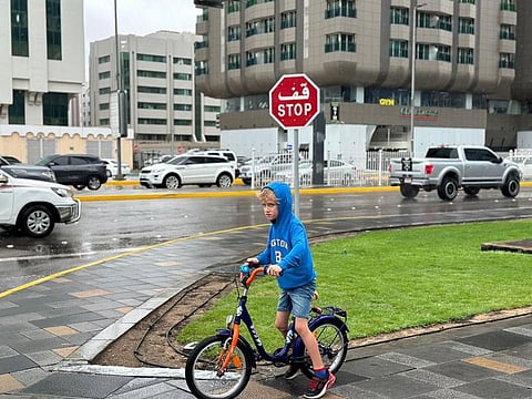 A child is seen enjoying the rain in Abu Dhabi. Public urged to follow safety as Abu Dhabi monitors weather