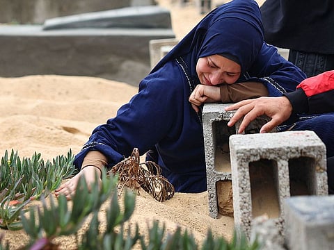 A woman cries over the grave of a loved one at a cemetery in Rafah in the southern Gaza Strip.