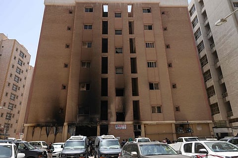Kuwaiti security forces gather outside a building which was ingulfed by fire. The identities and nationalities of the nine convicted individuals have not been publicly disclosed.