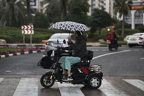 People pull out their umbrellas and hoodies to avoid getting wet on their way home from work as rain comes down in Dubai during the evening time.