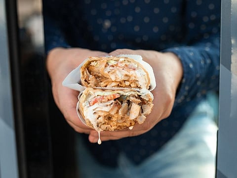 Shawarma consists of thin-sliced meat cooked on a rotisserie and filled with fries and sauces