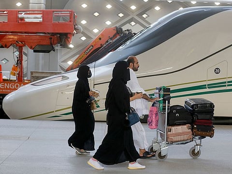 Pilgrims on their way to Makkah walk past the Haramain High-Speed Railway train in the holy city of Medina, Saudi Arabia, Thursday, Aug. 8, 2019.