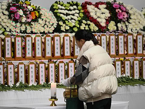 A mourner pays her respects at a memorial altar for victims of the Jeju Air plane crash, at Muan Sports Park in Muan on December 30, 2024.