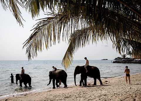 Tourists ride elephants on a beach on Thailand’s island of Koh Chang, on April 9, 2023.