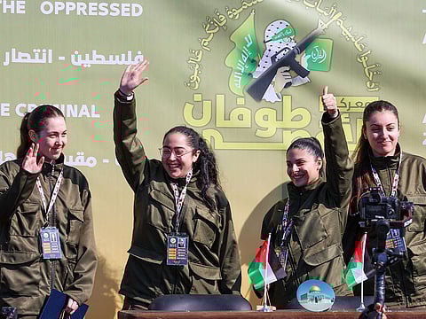 Four Israeli hostages wave on a stage before Hamas fighters hand them over to a team from the Red Cross in Gaza City on January 25, 2025.