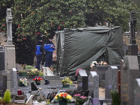 French gendarmes stand guard as a tarpaulin covers the vandalised tombstone of the late far-right leader Jean-Marie Le Pen, in La Trinite-sur-Mer, western France, on January 31, 2025.
