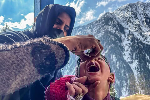 A health worker administers polio drops to a child during a door-to-door vaccination campaign amidst heavy snow in the Bakwali-Surgan area of Pakistan-administered Kashmir.