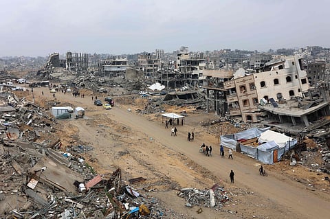 People walk amid collapsed buildings along Saftawi street in Jabalia in the northern Gaza Strip on February 5, 2025.
