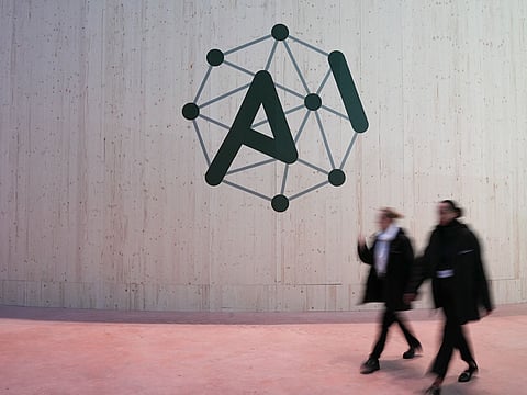 Attendees walk pass an AI Action Summit logo sign at the Grand Palais in Paris, France, on Monday, Feb. 10, 2025.