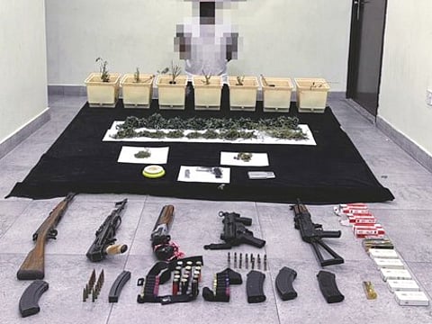 Police handout photo shows a suspect with a seized haul of drugs and firearms seized in a raid in Kuwait.