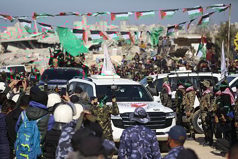 Red Cross vehicles, carrying Israeli hotages handed over by Palestinian militants, drive past the crowd in Khan Yunis in the southern Gaza Strip on February 15, 2025 during the sixth hostage-prisoner exchange between Hamas and Israel.