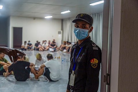 A security guard stands guard next to a room full of alleged scam centre workers and victims during a crackdown operation by the Karen Border Guard Force (BGF) on illicit activity in Shwe Kokko in Myanmar's eastern Myawaddy township on February 14, 2025.