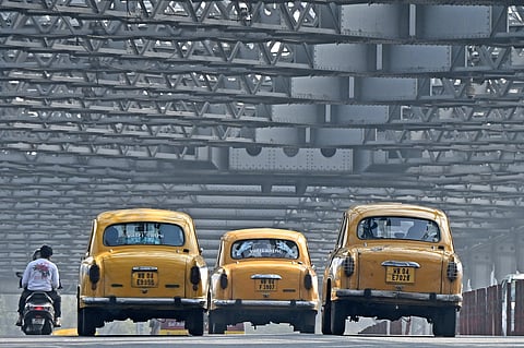 Passengers riding Hindustan Ambassador yellow taxis along the Howrah bridge in Kolkata.
