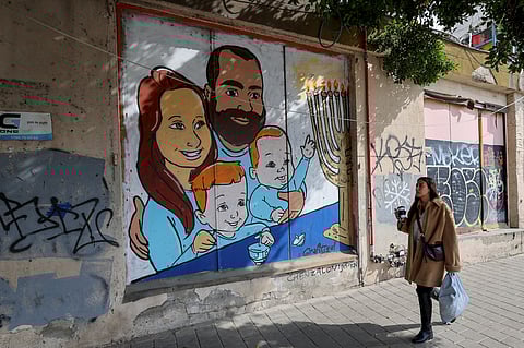 A woman walks past a mural paiting representing the Bibas family, held by Hamas in Gaza since October 7, 2023 on a wall in the Israeli coastal city of Tel Aviv, on February 19, 2025.