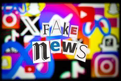 An illustration photo shows letters cut out of newspapers arranged to read "Fake news", set up in front of a screen displaying social media logos, in Mulhouse, eastern France, on February 20, 2025. A Kuwaiti citizen has been arrested for operating 16 fake social media accounts.