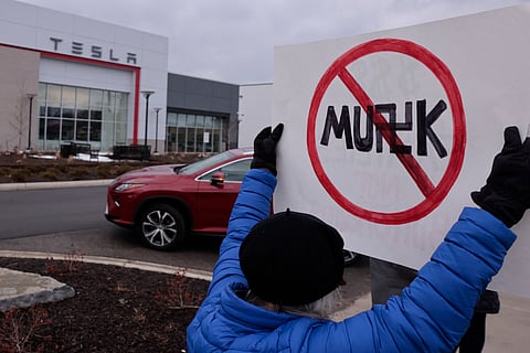 A person holds up a sign during a protest against Elon Musk outside of a Tesla dealership in West Bloomfield, Michigan, on February 27, 2025.