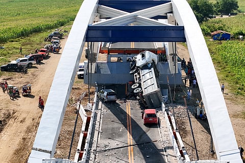 An aerial view shows damaged vehicles on a section of a collapsed bridge in Santa Maria town, Isabela province on February 28, 2025.