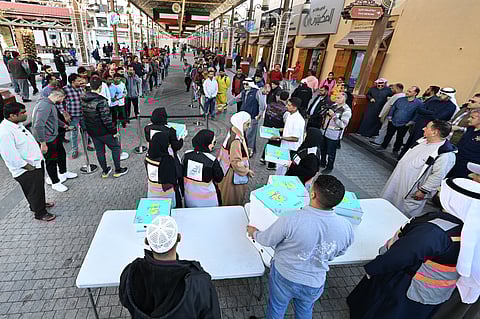 Volunteers pass out donated 'iftar' meals to worshippers, to end their day-long fast, at the Al Mubarakiya market in Kuwait City on March 1, 2025.