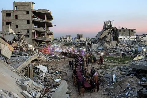 People gather by the rubble of destroyed buildings for a mass gathering for a communal iftar meal on the second day of Ramadan in Al Dahduh in Gaza City's Tal Al Hawa district on March 2.