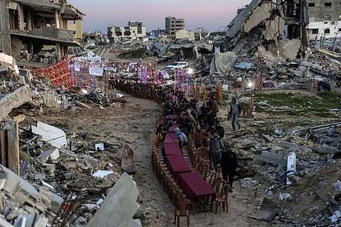 People gather by the rubble of destroyed buildings for iftar meal on the second day of Ramadan in the area of Al Dahduh in Gaza City's Tal Al Hawa district