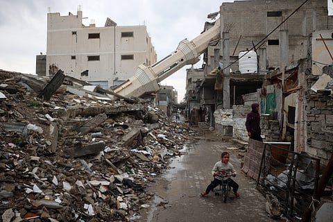 A Palestinian child rides a bicycle near a fallen minaret of a destroyed mosque during the Muslim holy fasting month of Ramadan, in the Nuseirat refugee camp in the central Gaza Strip on March 7, 2025.