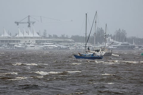 A man stands on a yacht as he prepares to move in high winds opposite the Mariner’s Cove Marina on the Gold Coast.