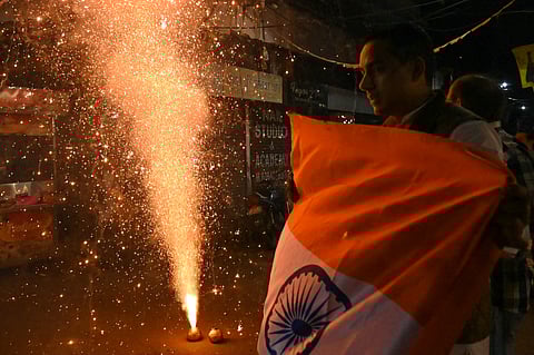 A cricket fan holds the national flag as fans celebrate India's victory in the ICC Champions Trophy One-Day International (ODI) final cricket match against New Zealand on a street in Amritsar, Punjab, on March 9.