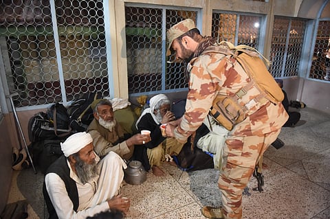 A soldier hands out tea to freed train passengers gathered at the Mach railway station, which has been turned into a makeshift hospital, after Pakistani security forces freed them following a security operation,