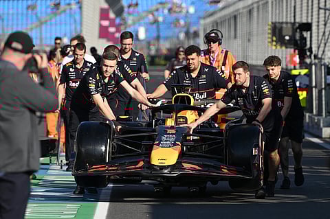 Mechanics push the car of Red Bull Racing's Dutch driver Max Verstappen at the Albert Park circuit in Melbourne on March 13, ahead of the Formula One Australian Grand Prix.
